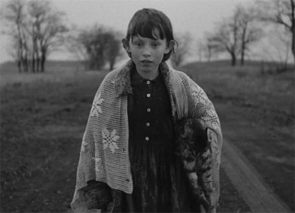 Estike (Erika Bók). En otro de los conocidos largos planos secuencia de Sátántangó, la cámara enfoca frontalmente a la niña. Parece como si todo su “recorrido” en la película confluyeran en esa mirada y en ese recorrido físico, pero también mental, por el camino que muestra la imagen. Drama y “locura”, pero, al mismo tiempo, determinación. Análisis cine Béla Tarr, crítica cinematográfica y difusión cultural.