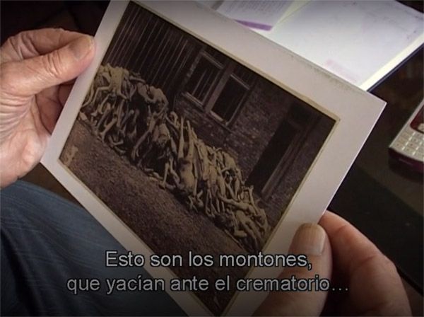 Hafner sostiene una fotografía de Willi de las Heras donde aparecen montones de cadáveres ante el crematorio un día después de la liberación.