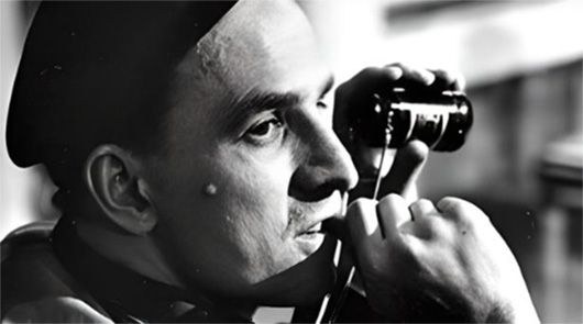 La imagen muestra a un hombre (Ingmar Bergman), director de películas como Los comulgantes, con un gorro mirando a través de un dispositivo de visión nocturna. La imagen es en blanco y negro, lo que aumenta la sensación de misterio y suspense.